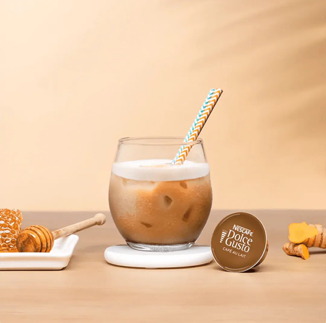 iced latte next to a coffee capsule